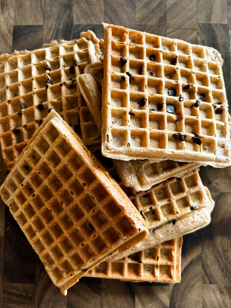 batch of belgian spelt waffles piled high on a wooden butcher block