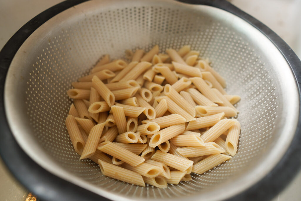 Colander filled with cooked penne pasta