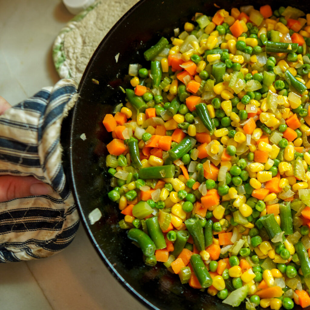 Cooking a hearty chicken pot pie filling in a large cast iron skillet