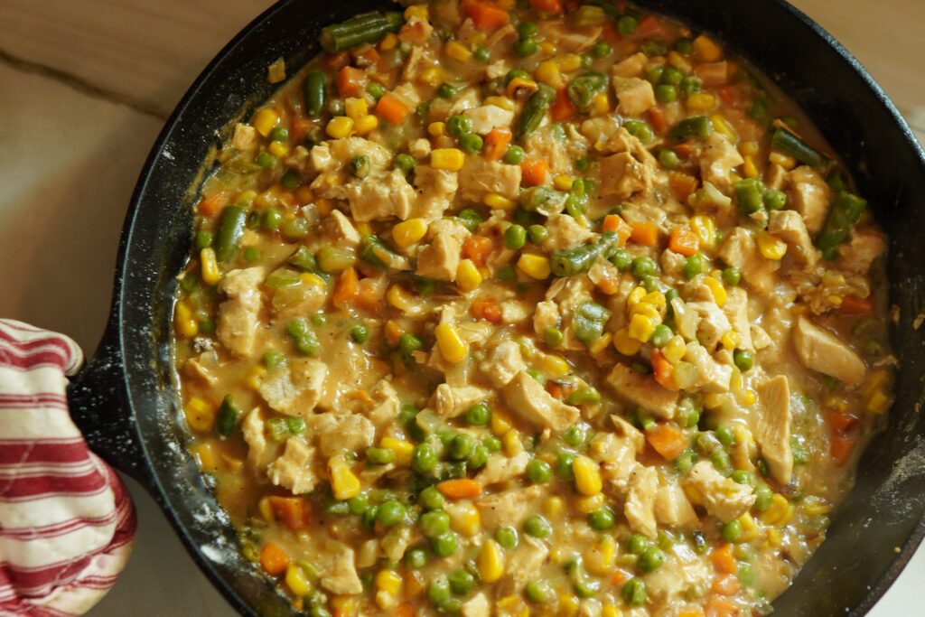 Cooking a hearty chicken pot pie filling in a large cast iron skillet