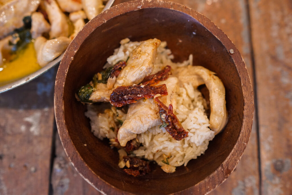 a serving of creamy tuscan chicken in a bowl sitting on a wooden table top