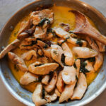 A skillet of creamy tuscan chicken with wooden spoon ready to serve