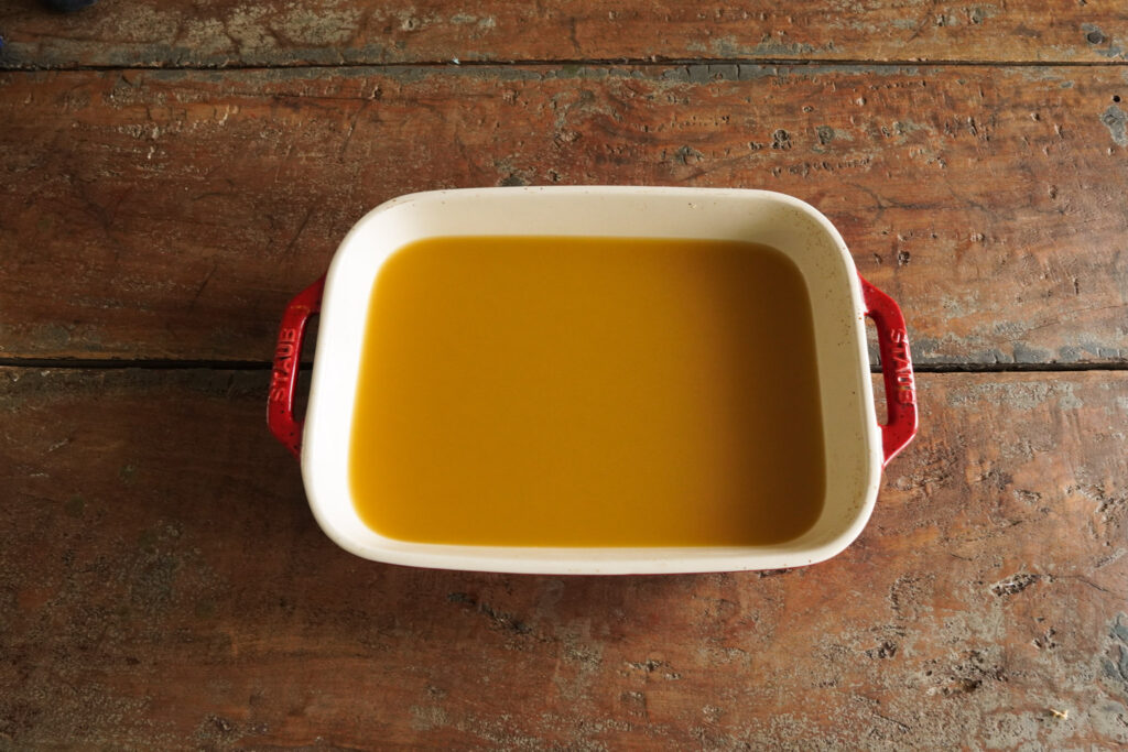 a pan of pineapple gummies sitting on a wooden table top waiting to be cut up