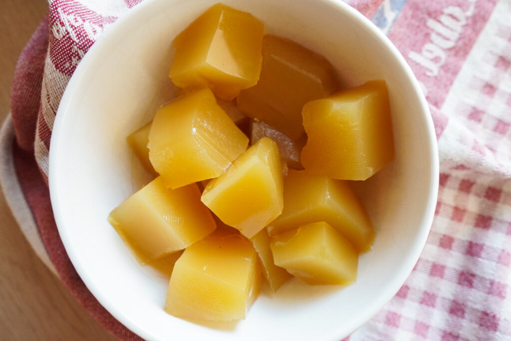 a white bowl of pineapple gummies sitting on a tea towel on a wooden counter top