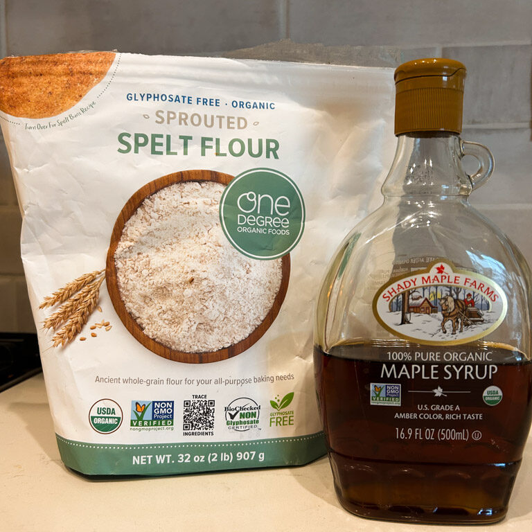 bag of spelt flour and jar of maple syrup sitting on a countertop