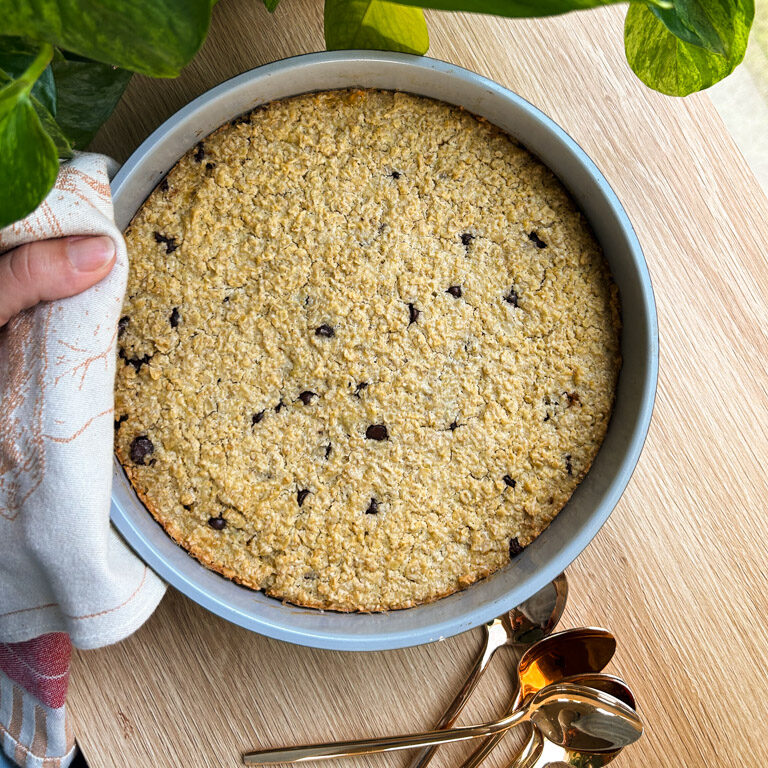 baker's hand uses a tea towel to place chocolate chip oatmeal bake on the counter to cool