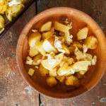 wooden bowl full of crispy seasoned potatoes and feta cheese