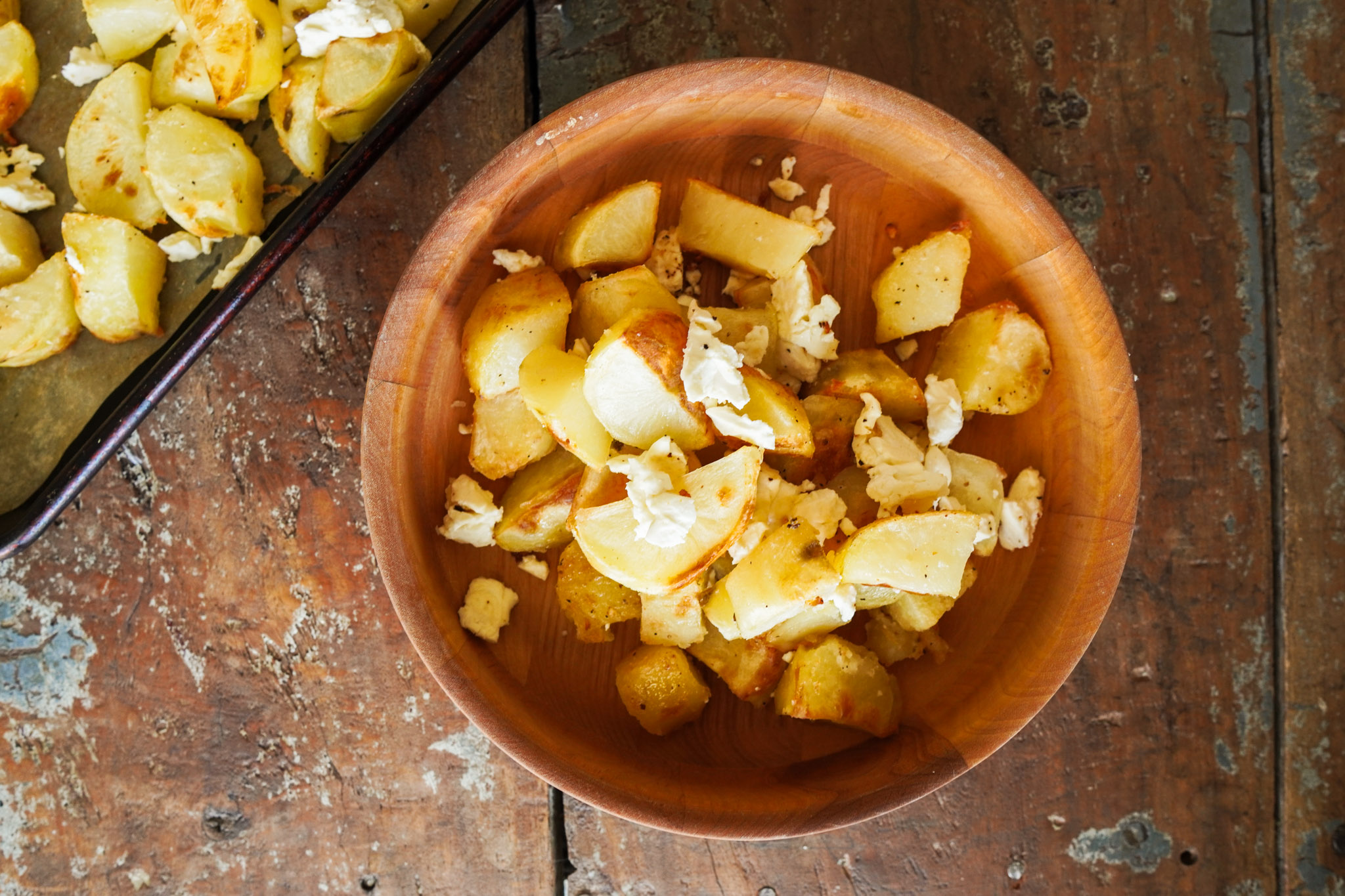wooden bowl full of crispy seasoned potatoes and feta cheese